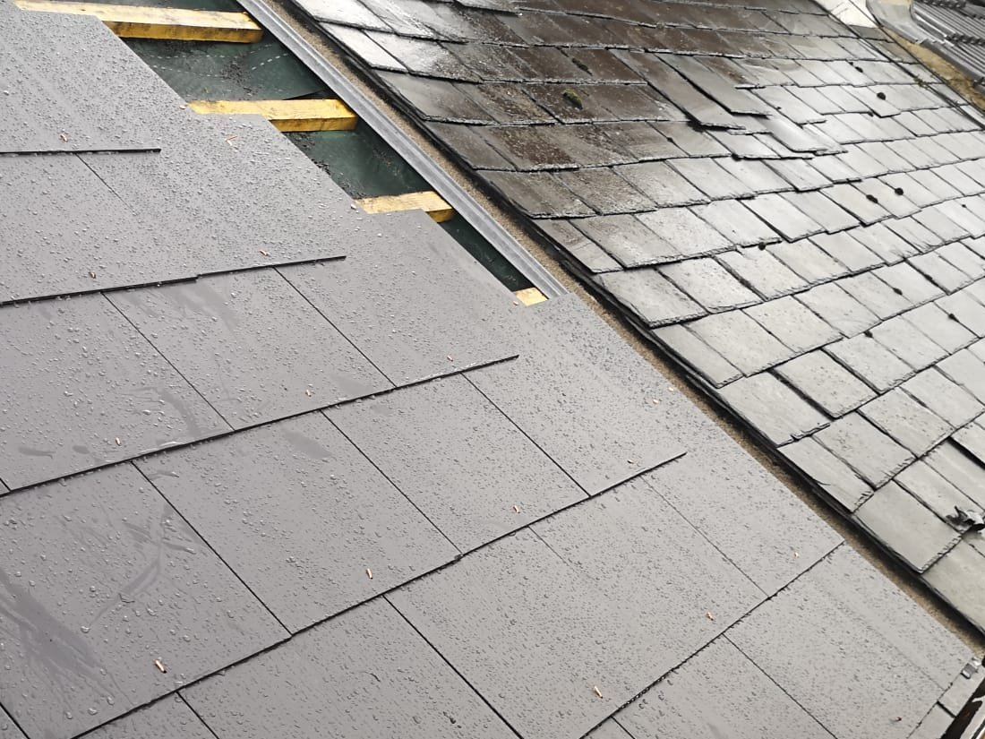 New slate roof being laid next to the old slate on a terraced house
